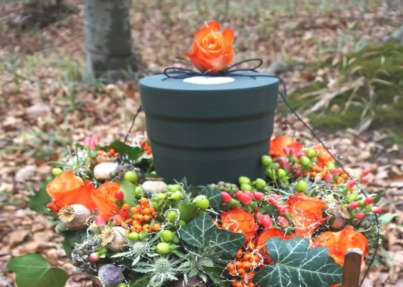 Urne im Wald mit Rosenkranz drum herum